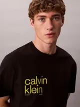 Remera de algodón negro Calvin Klein con cuello redondo, manga corta y logotipo estampado en amarillo alineado en la parte derecha del pecho.