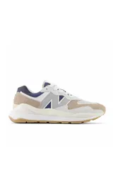 Championes urbanos New Balance modelo 57/40, con diseño de paneles en tonos beige, blanco y azul marino. Presentan una entresuela gruesa y suela de goma color caramelo.
