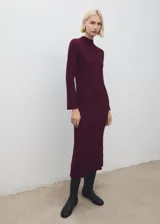 Vestido midi de punto acanalado en color bordó, con cuello perkins y mangas largas acampanadas. Presenta un diseño entallado al cuerpo.