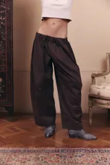 Pantalón de gabardina impermeable color marrón chocolate, con silueta amplia y relajada. Presenta cintura elastizada con pinzas delanteras que aportan volumen y movimiento a la prenda.