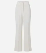 Pantalón flare de tejido plano color blanco, con trabillas en la cintura, cierre tradicional, frisos delanteros y bolsillos falsos atrás.