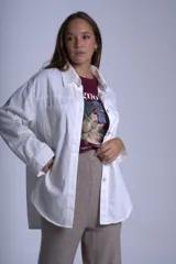 Sobrecamisa color beige confeccionada en gabardina, de corte holgado, con cuello camisero, cierre frontal con botones, dos bolsillos de parche en el pecho y mangas largas con puños abotonados.