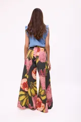 Pantalón ancho de tiro alto, color negro, con estampado vibrante de frutas tropicales en tonos rosados, amarillos y rojos.