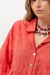 Vestido corto coral de broderie, con cuello camisero, cierre frontal de botones, mangas tres cuartos con volados y diseño escalonado en la falda.