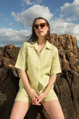 Camisa de manga corta oversize en lino rayado, con cuello camisero, cierre frontal con botones y bordado playero en el frente.