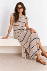 Vestido largo de punto color visón, sin mangas y con cuello redondo, diseño a rayas horizontales en tonos azul, blanco y bordó, y tajos laterales en la falda.