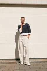 Chaqueta gris de cuello redondo y manga tres cuartos, con detalle de volantes de popelín blanco en el cuello, puños y bajo. Cierre frontal con botones.