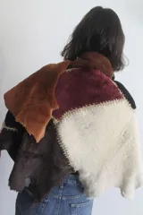 Ruana artesanal confeccionada con piezas de napalán unidas mediante técnica de crochet, con diseño de parches en tonos tierra y texturas de piel sintética.