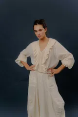 Camisa blanca de algodón con escote en V, volados delanteros y detalles de encaje en el frente y las mangas.