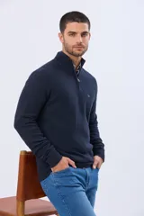 Buzo de punto texturado color azul marino, con cuello alto y cierre frontal parcial. Presenta puños y ruedo acanalados, con un pequeño logo bordado en el pecho.