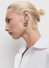 Camisa de corte recto en tejido mezcla, con cuello camisero de solapas amplias, cierre frontal de botones ocultos bajo tapeta y mangas largas con puños abotonados.