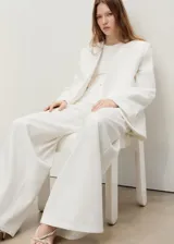 Jeans wide leg blancos de tiro alto, confeccionados en tejido 100% algodón denim. Presentan diseño de cinco bolsillos, trabillas para cinturón y cierre frontal con cremallera y botón.