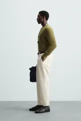Pantalón chino de algodón color crema, corte regular fit, con cierre frontal de cremallera y botón, bolsillos delanteros y bolsillos traseros de vivo con botón.