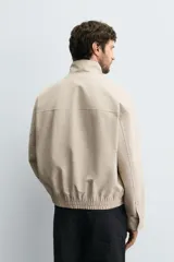 Cazadora regular fit de algodón color beige, con cuello subido, cierre frontal de cremallera y bolsillos laterales de vivo.