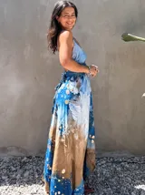 Vestido largo verde con diseño estampado tipo tie-dye y detalles dorados, de corte fluido, un solo hombro y diseño amplio.