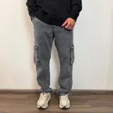 Pantalón tipo jean cargo de corte recto y tiro medio, en color azul claro lavado. Presenta bolsillos laterales con solapa y cierre de botón y cremallera.