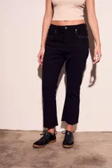 Pantalón de jean negro con corte flare, tiro medio y detalles de tachas plateadas en los bolsillos delanteros.
