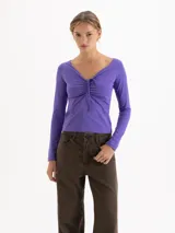 Top de manga larga color violeta, con escote en V y detalle de fruncido central regulable mediante lazos finos en el delantero. Presenta un ajuste entallado al cuerpo.