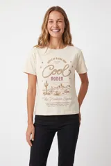 Remera color beige con estampa frontal de estilo western que incluye la frase 'Cool Rodeo' y un paisaje desértico con cactus.