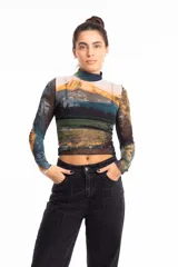 Remera crop top de mangas largas y cuello alto, confeccionada en tejido de red transparente con estampado de paisaje montañoso.