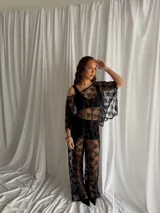 Pantalón negro de encaje transparente, de tiro medio y corte holgado con diseño de piernas anchas.