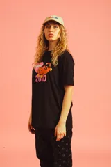 Remera negra de algodón con estampado de un tigre naranja y negro, un corazón rosa con la palabra 'Barrio' y el número '2000'.