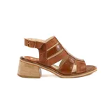 Sandalia de cuero color marrón, con diseño de tiras cruzadas, taco ancho de madera y tira ajustable con hebilla en el tobillo.