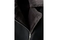 Chaqueta estilo aviador de cuero sintético color negro, con interior y cuello de corderito sintético en tono gris oscuro. Cuenta con cierre frontal cruzado, bolsillos con cierre y detalles de hebillas en las muñecas.