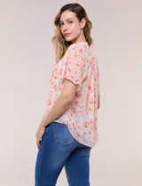 Blusa blanca de doble capa de gasa con estampado floral en tonos amarillos, celestes y rosados, escote en V con frunces y mangas cortas con volados amplios.