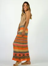 Pollera larga tejida a crochet con diseño de rayas horizontales en tonos naranja, fucsia y morado.