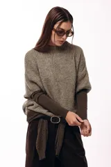 Sweater de tejido de punto grueso con silueta amplia y mangas 3/4. Presenta un diseño de calce relajado con cuello redondo y textura voluminosa.