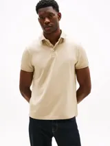 Chomba color beige con tejido jacquard, cuello tipo chomba, billetera de dos botones, logo de Tommy Hilfiger bordado en la manga y corte regular.