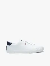 Zapatillas urbanas Tommy Hilfiger de corte bajo, color blanco con detalle azul en el talón. Tienen diseño con cordones, suela de goma blanca y pequeño logo bordado en el lateral.