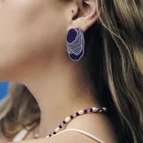 Aros colgantes de acrílico color violeta con diseño de ondas blancas.