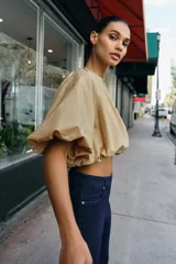 Cuerpo corto de cuello redondo con frunces, escote en pico con lazada y mangas cortas abullonadas con elástico interior.