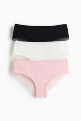 Pack de tres bombachas hipster confeccionadas en punto de algodón y encaje, en colores negro, blanco y rosado. Presentan cintura estándar con borde festoneado, detalles de encaje lateral y cobertura media en la parte trasera.