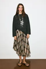 Jersey de punto color negro con cuello redondo y manga larga, de diseño amplio y bajo asimétrico.