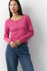 Remera blanca de manga larga con cuello redondo y costuras a la vista.