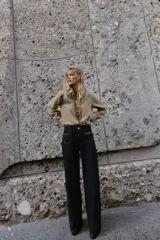 Jeans de mezclilla azul oscuro, tiro medio, corte pierna ancha (wide leg). Presenta bolsillos delanteros de parche con detalle de cadena metálica decorativa.