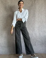 Jean de tiro alto y corte wide leg, color gris oscuro con costuras a contratono. Presenta un diseño de paneles verticales en el frente y cierre frontal con botón metálico.