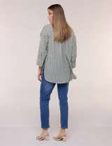 Blusa de silueta holgada a rayas verdes y blancas, confeccionada en tela liviana con textura arrugada. Presenta cuello en V profundo con botones frontales, mangas 3/4 de hombro caído y ruedo asimétrico con aberturas laterales.