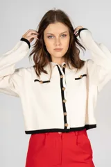 Saco corto color crema con ribete negro, cuello camisero, cierre frontal con botones dorados y bolsillos simulados con ribete negro y botón dorado.