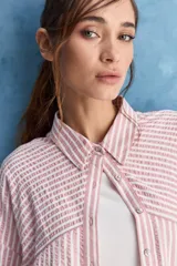 Camisa de calce relajado a rayas rosadas y blancas, con cuello camisero clásico y frente abotonado. Presenta recortes con cambio de dirección en las rayas y silueta amplia.