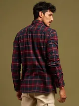 Camisa de franela a cuadros azules y grises, de manga larga con puños abotonados y dos bolsillos frontales con solapa abotonada.