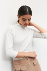 Polera de algodón color blanco, con cuello alto y mangas tres cuartos. Presenta un diseño ajustado al cuerpo con costuras decorativas en las sisas.