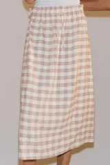 Falda midi recta de tiro medio con estampado a cuadros en tonos rosados y blancos sobre base beige, confeccionada en hilatura con mezcla de viscosa. Cuenta con cintura elástica ajustable con cordones y bajo recto.