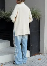 Buzo oversize color crema de tejido elastizado, cuello alto, puños ajustados y tajos laterales.