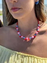 Collar corto con cuentas de cristales checos y mostacillas de colores rosa, celeste y rojo. Se cierra con cadena de acero quirúrgico y ganchito para regular el largo.