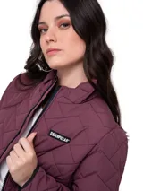 Chaqueta acolchada color bordó con diseño de costuras en zigzag. Presenta cierre frontal central, bolsillos laterales con cierre y logo de la marca en el pecho. Cuenta con cuello alto y puños internos de punto acanalado para mayor protección.