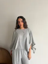 Conjunto de dos piezas de lanilla en color gris melange, compuesto por una blusa de corte amplio con mangas murciélago y escote bote, y un pantalón recto con bolsillos laterales.